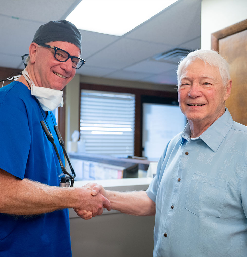 dr beard shaking hand of light blue shirt man